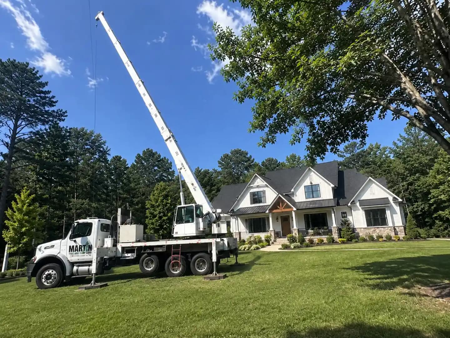 Coordinated crane lifting a tree section over a residential structure on a Martin Tree and Turf Care removal in Upstate SC
