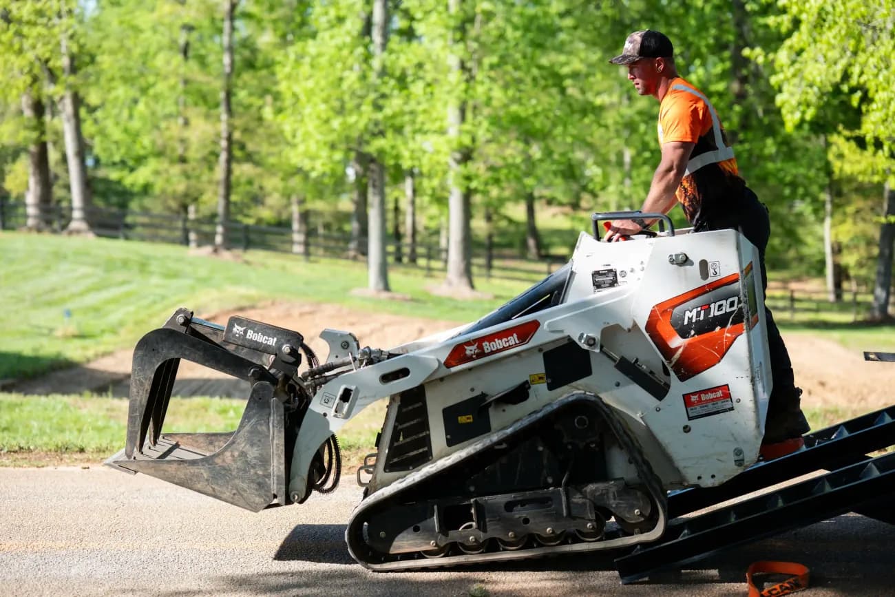 Martin Tree and Turf Care mini skid steer moving a log on a residential property in Upstate SC — minimal turf impact